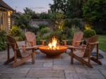 Corten steel fire bowl with chairs around it in a backyard at dusk