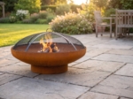 Rust-patina fire bowl with the domed spark screen in place
