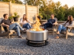 Stainless fire pit surrounded by Adirondack chairs in late afternoon